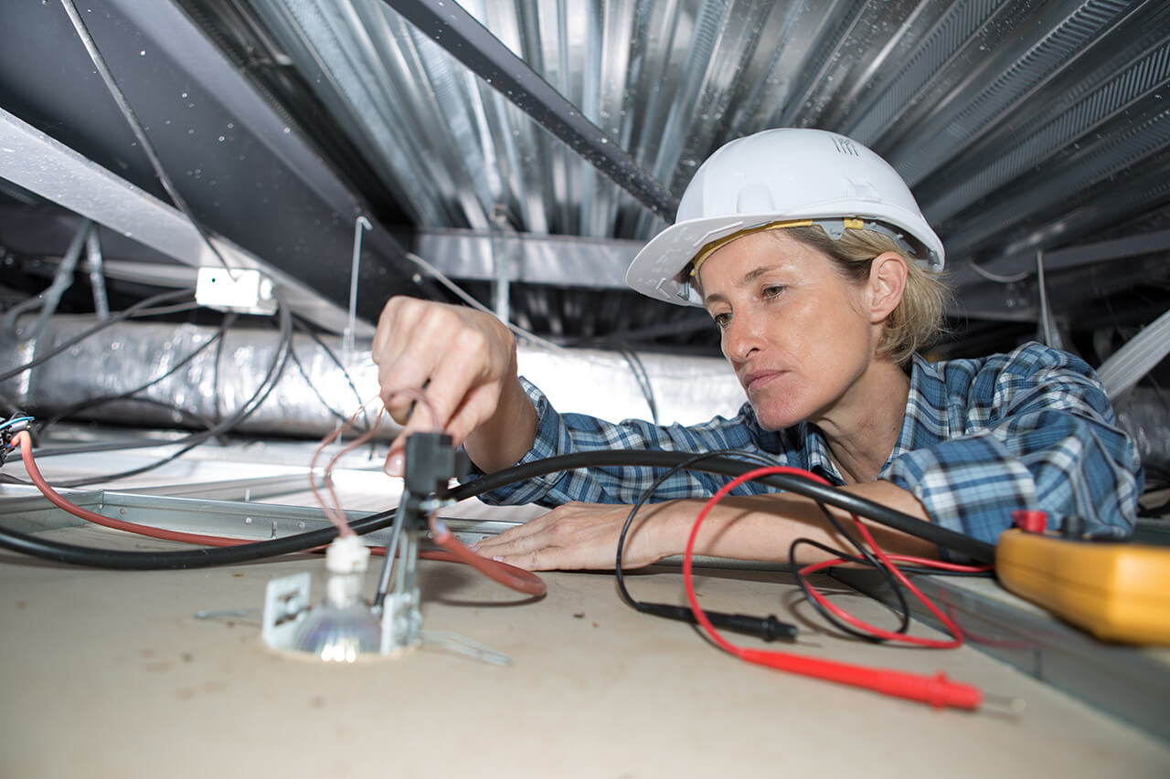 electrician installing wiring in attic of home