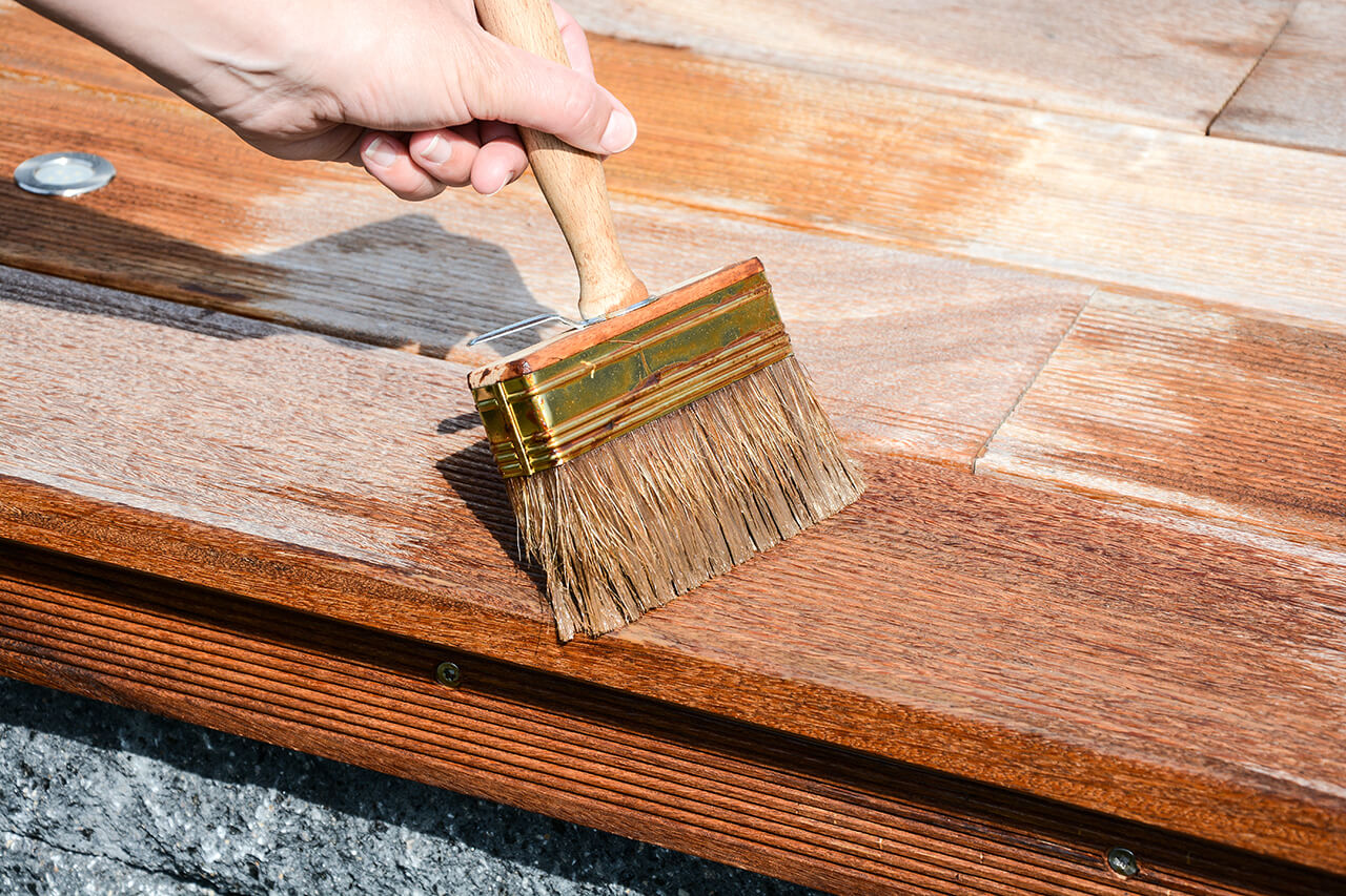 sealing a wooden deck with a paintbrush
