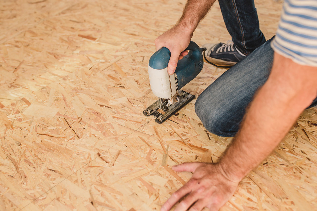 A worker installing subfloor from sheets of plywood