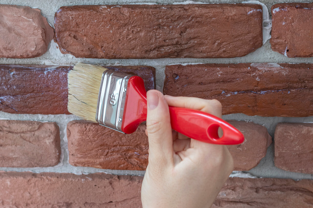 staining and sealing a brick wall with a paintbrush