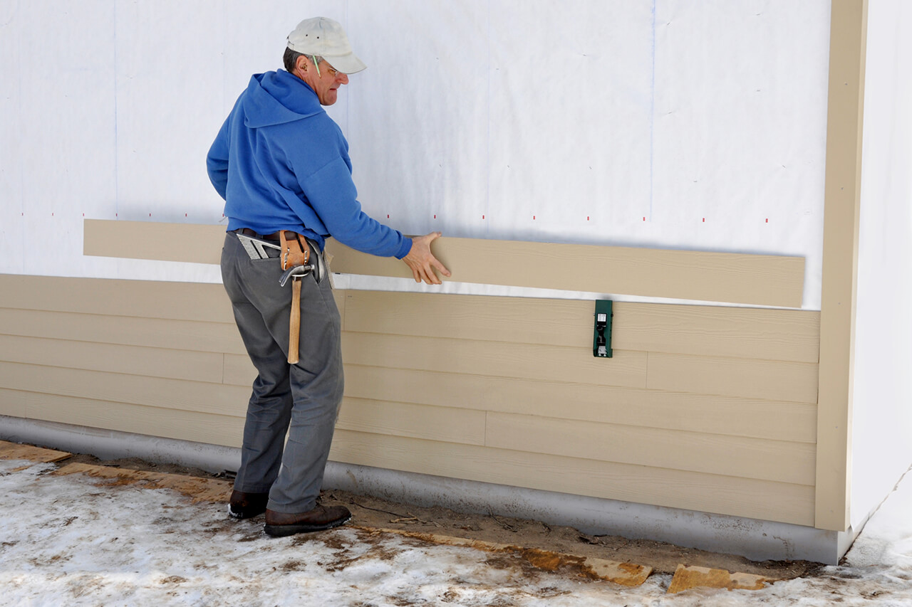 carpenter installing siding on a home