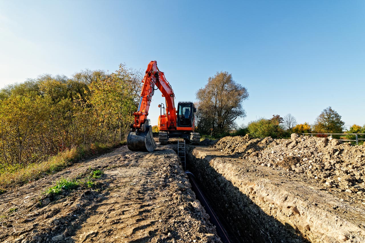 backhoe digging a deep trench in backyard