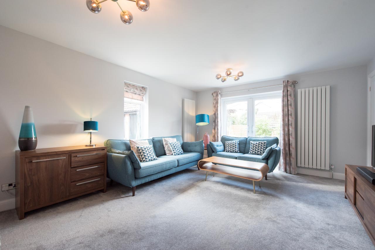 A view of a carpeted living room with retro looking blue sofa