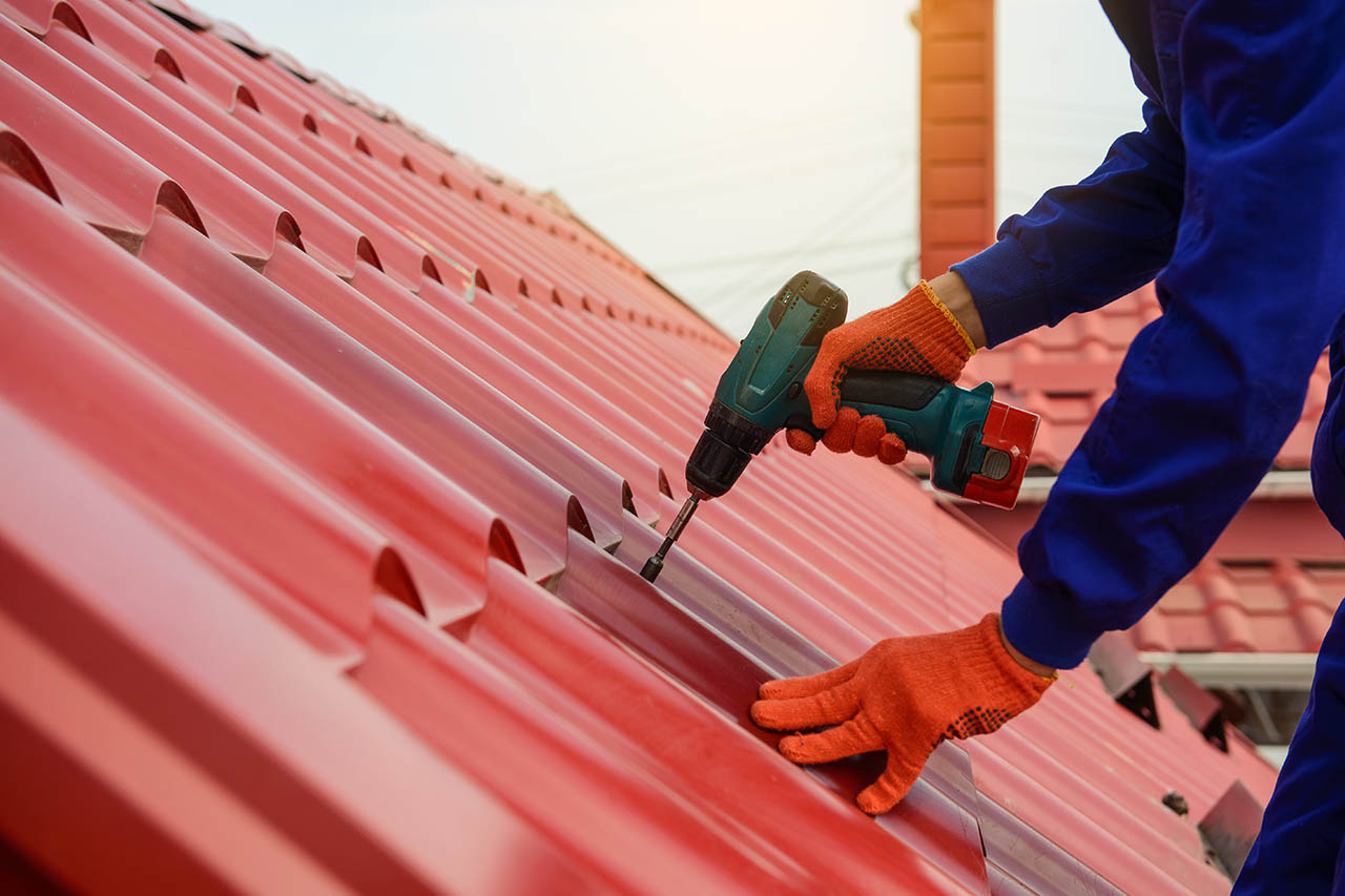 Roofer repairing metal roof with power tools