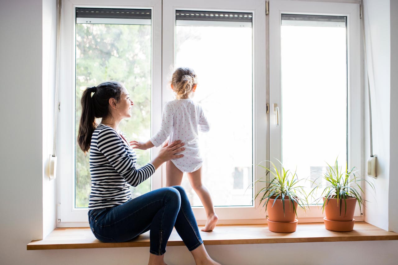 Mother with her little daughter looking out of window
